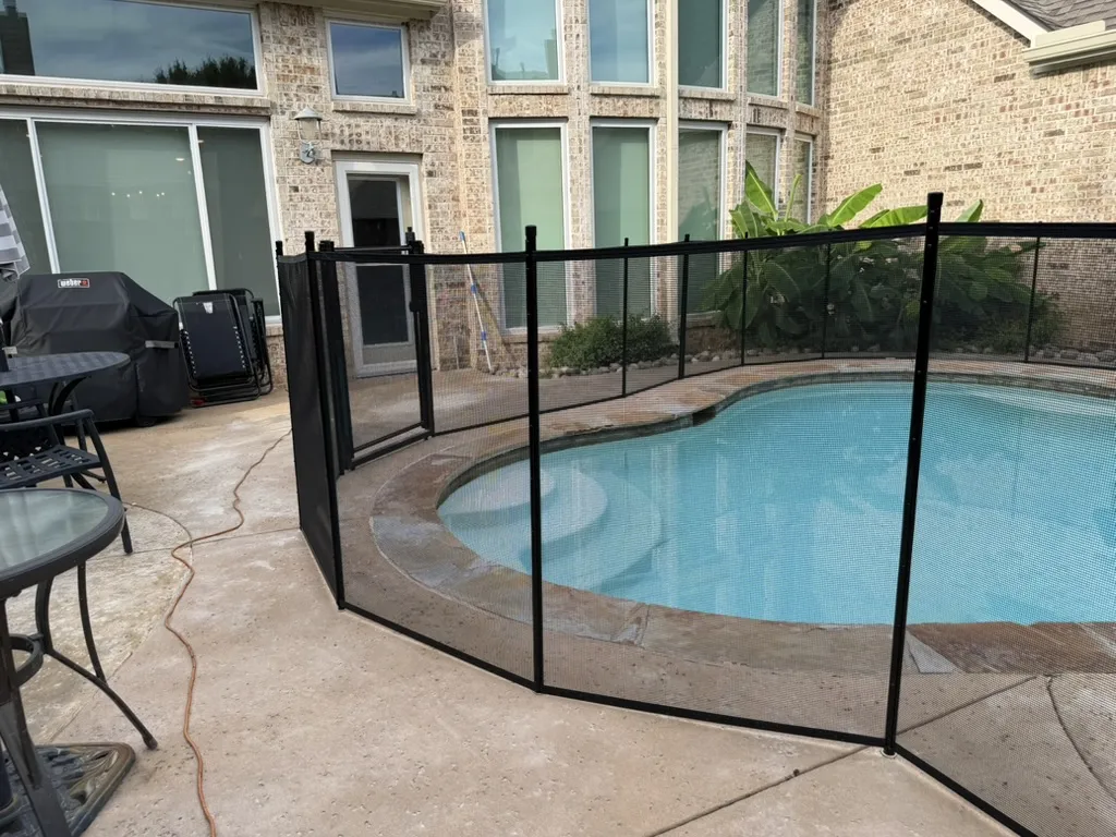 Black removable mesh pool safety fence installed around a backyard pool in Dallas, TX